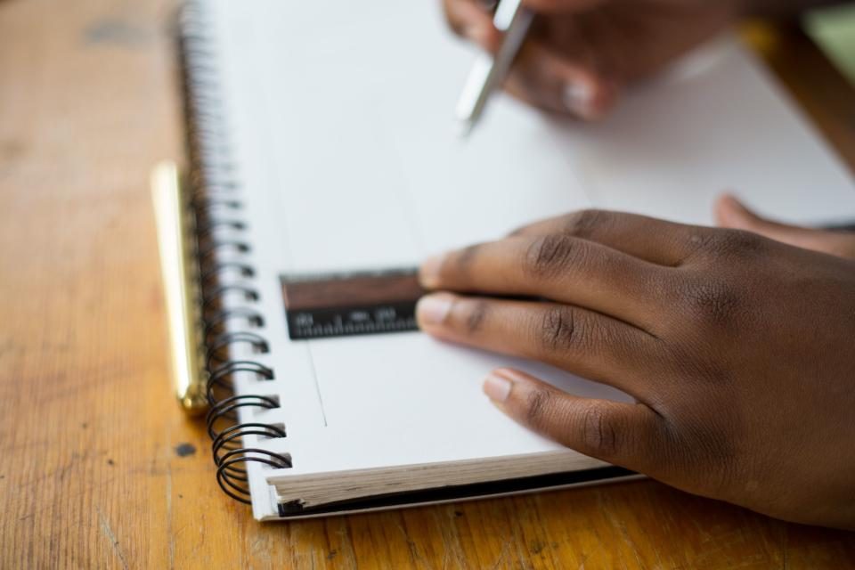 Une main trace un trait à la règle dans un cahier